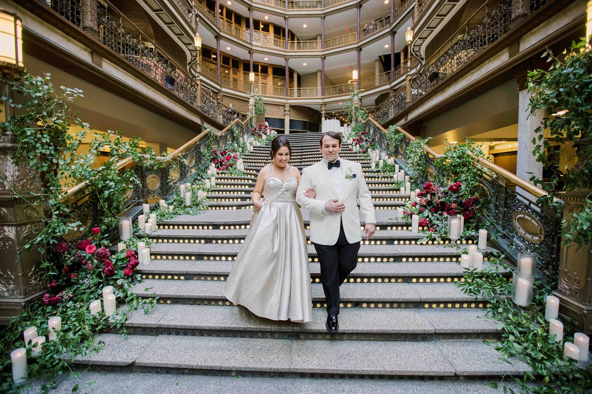 Bride and Groom walk down main staircase at Hyatt Cleveland in winter for their wedding entrance, flowers by HeatherLily