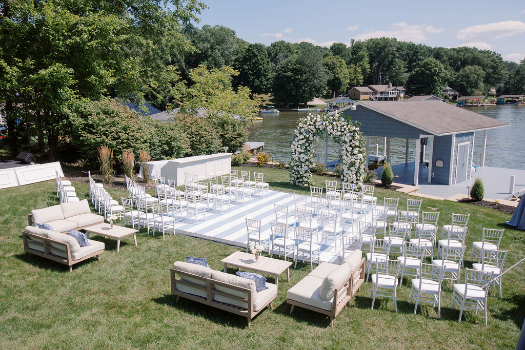 Lake front wedding ceremony in front of boathouse in Ohio by HeatherLily with floral arch and dance floor.